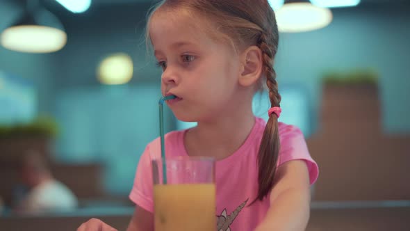 Little Girl Drinks Orange Juice Using Drinking Straw
