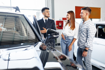 Young couple choosing a car at the dealership with manager helping / Photodune, Misc