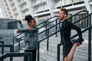Doing stretches. European man and african american woman in sportive clothes have workout together / Photodune, Misc