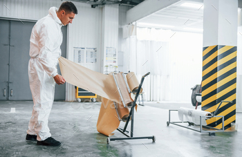 Caucasian automobile repairman in uniform works in garage / Photodune, Misc