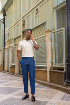 Full length shot of young African businessman outdoors talking on mobile phone / Photodune, Misc