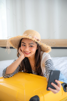 Happy asian young female selfie photo with smathphon, luggage, hat