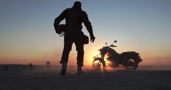 A Man Sits on a Motorcycle at Sunset