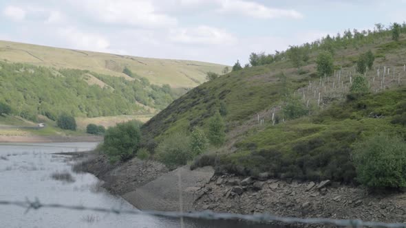 Butterley reservoir  and Yorkshire hills wide tilting shot through fence