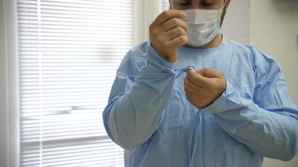 the doctor wears a protective sterile gown before surgery