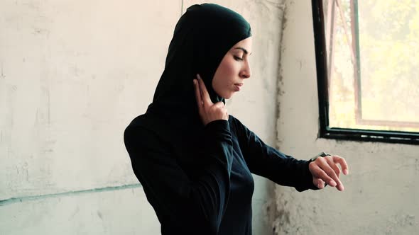 An arabian sports woman wearing national hijab is measuring her pulse
