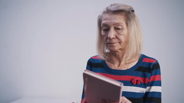 Elderly Woman Opening Her Diary and Reading From It