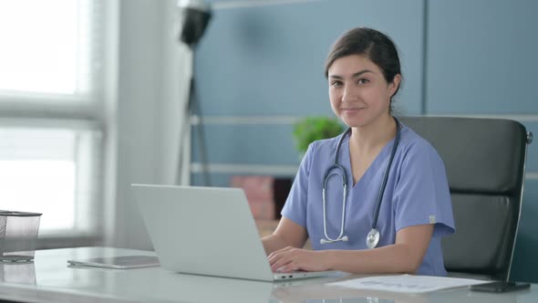 Indian Female Doctor Showing Thumbs Up Sign While using Laptop in Office