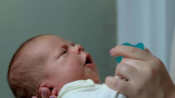 A Newborn Baby Is Unhappy When A Pacifier Is Taken From Him