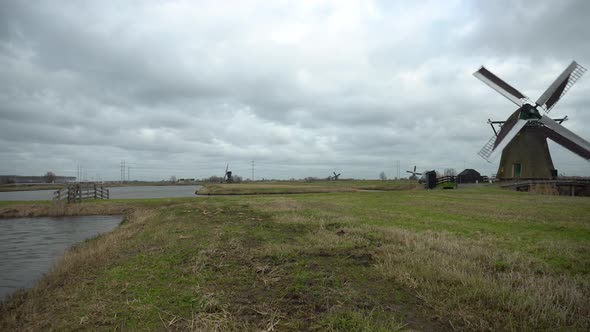 Dutch windmills turning in wetlands, camera pan reveal