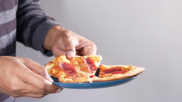 Man Hand Picking Slice of Pizza From a Plate