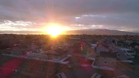 Flying over houses in neighborhood into the sun setting