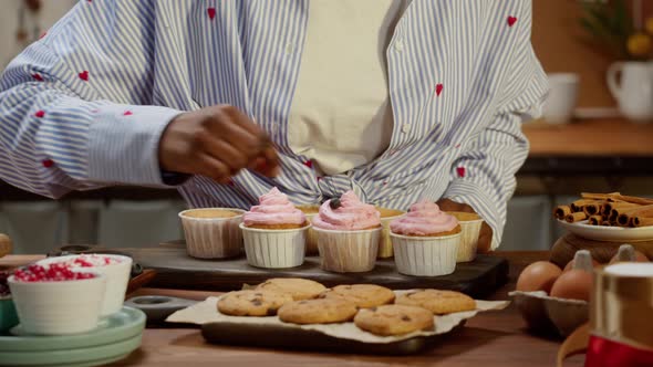 African American Chef Decorating Cupcakes with Berries and Confetti Closeup