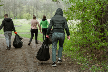 A group of volunteers with garbage bags are cleaning the forest. / Photodune, Misc