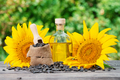 Bottle of sunflower oil and sunflower with seeds on wooden table - PhotoDune Item for Sale