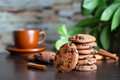 Oatmeal cookies with chocolate on the table against background of cup of coffee and green leaves - PhotoDune Item for Sale