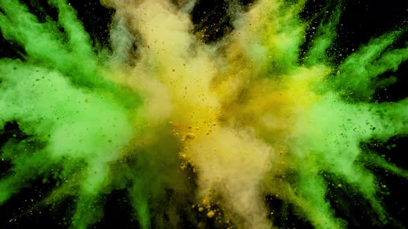 Colorful powder/particles fly after being exploded against black background. Slow Motion.