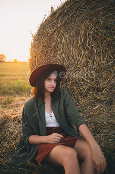 Beautiful woman in hat relaxing at haystacks enjoying evening sunset in summer field. Tranquility / Photodune, Misc