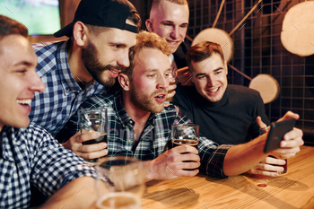 Uses phone. Group of people together indoors in the pub have fun at weekend time / Photodune, Misc