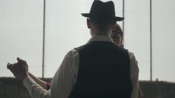 Man in Fedora Hat, Classical Suits and Woman in Style Cloth Dancing in Dirty Place.