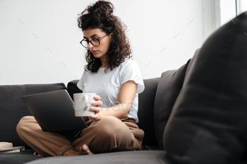Serious brunette young woman working with laptop and drinking coffee / Photodune, Misc