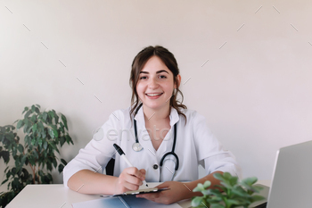 Smiling doctor writes something in the patient's medical history / Photodune, Misc