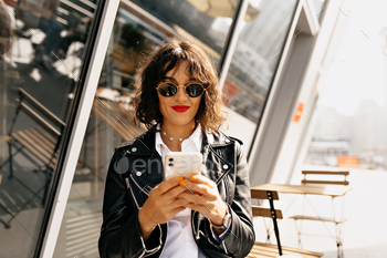 Modern stylish woman with short hairstyle wearing sunglasses using smartphone / Photodune, Misc