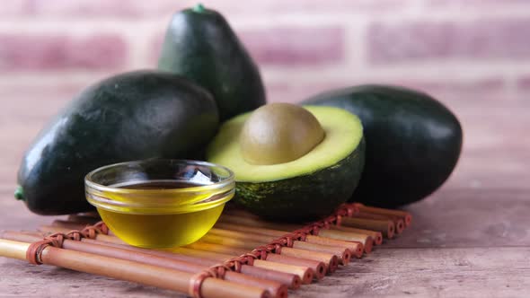 Oil and Slice of Avocado on Wooden Table