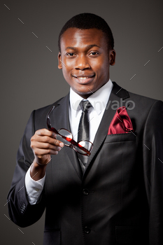 Young handsome african businessman in grey costume, white shirt, tie and glasses / Photodune, Misc
