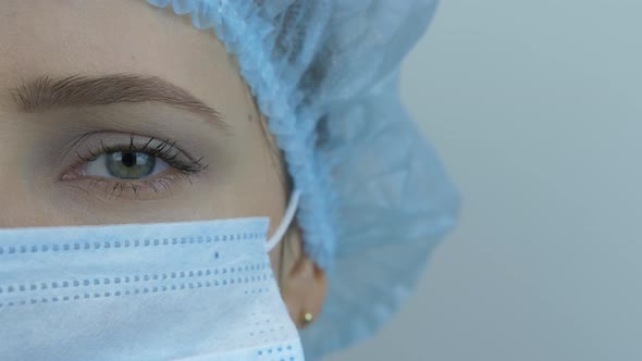 Portrait of young female scientist in medical cap, doctor uniform and protective face mask.