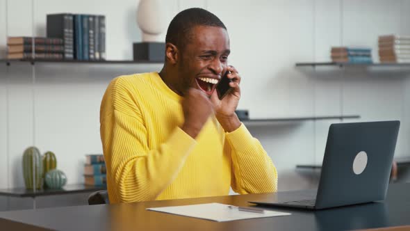 Smiling male talking on the phone while sitting at the desk