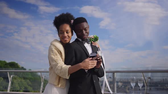 Happy Wealthy African American Bride and Groom Admiring Wedding Rings Smiling Hugging