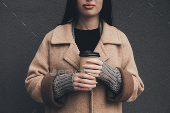 cropped view of woman in coat holding disposable cup of coffee / Photodune, Misc