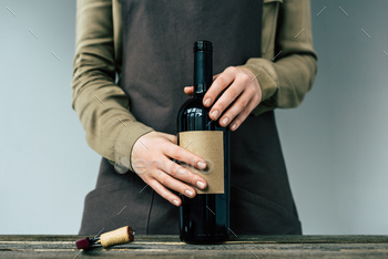 Woman in apron holding open bottle of red wine / Photodune, Misc