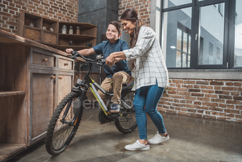 Young mother teaching her son how to ride a bicycle at home / Photodune, Misc