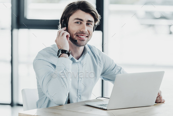 smiling call center worker with laptop looking at camera while sitting at workplace / Photodune, Misc