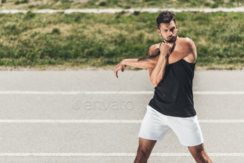 handsome young sportsman stretching on running track at sport playground / Photodune, Misc