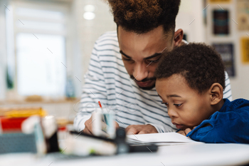 Serious african american father doing homework with his focused son / Photodune, Misc
