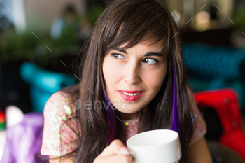 Portrait of young stylish trendy woman with multi-coloured strand in hair sits in cafe / Photodune, Misc