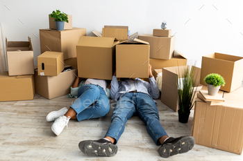 Moving day. Tired african american couple with cardboard boxes on heads, being tired in unpacking / Photodune, Misc