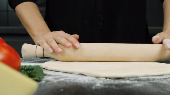 Hands are rolling out dough with rolling pin