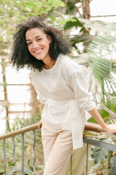 African American girl with an afro hairstyle smiling in tropical garden or forest nature background. / Photodune, Misc