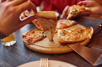 Close up view of people that taking and eating pizza indoors together / Photodune, Misc