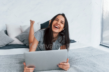 Young beautiful woman in casual clothes lying down at home alone with laptop / Photodune, Misc