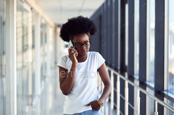 Young african american female passanger in casual clothes is in airport with phone / Photodune, Misc