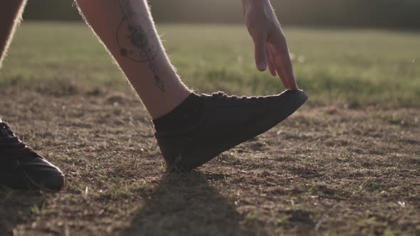 Man Stretching His Legs Before a Run Whilst Being Silhouetted By The Evening Sun - Ungraded