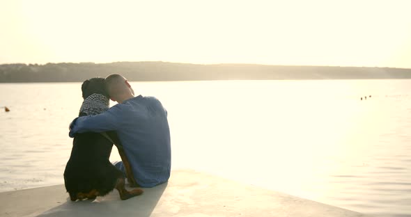 Man and Dog Sitting on the Dock at a Lake