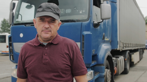 Professional Truck Driver Stands In Front Of Semi Truck