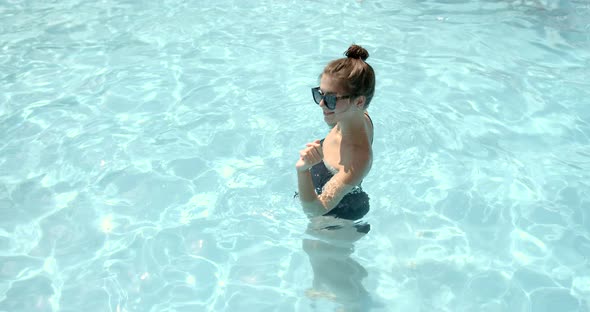 Young Woman in Sunglasses is Dancing in Swimming Pool in a Water Park