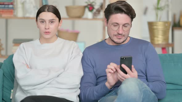 Hispanic Women Feeling Angry Next To Male Partner Busy with Phone